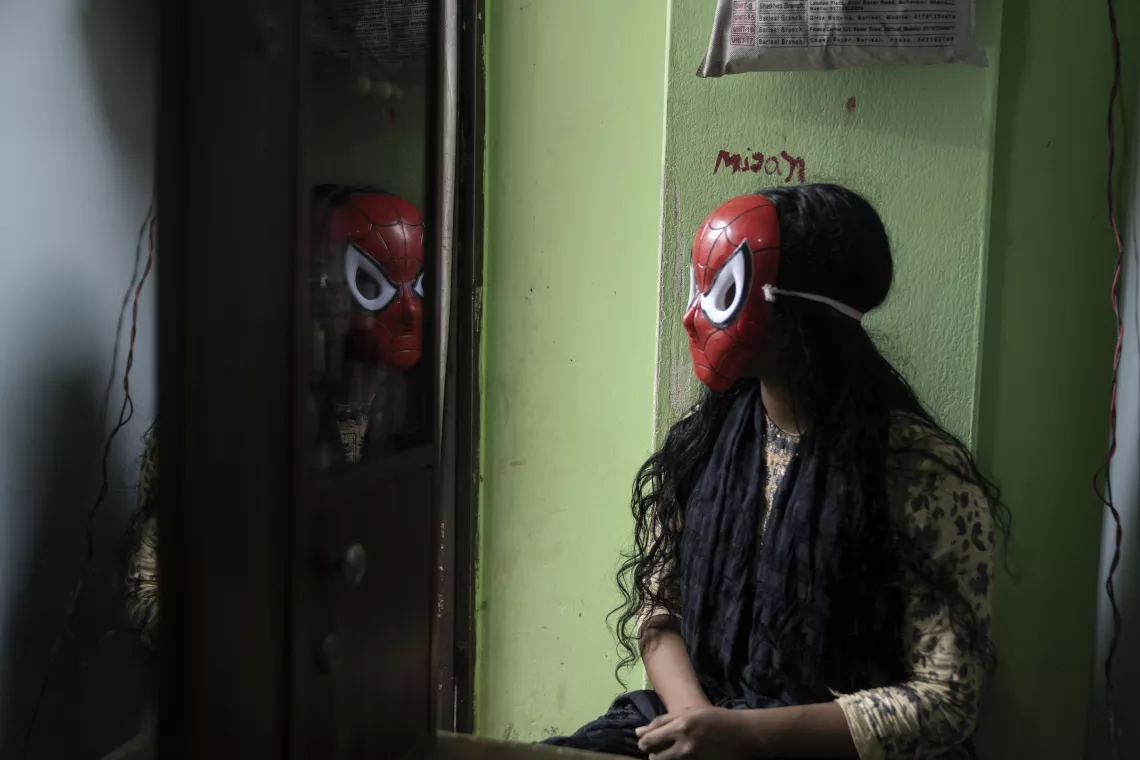 A girl looking at mirror wearing spider man mask 