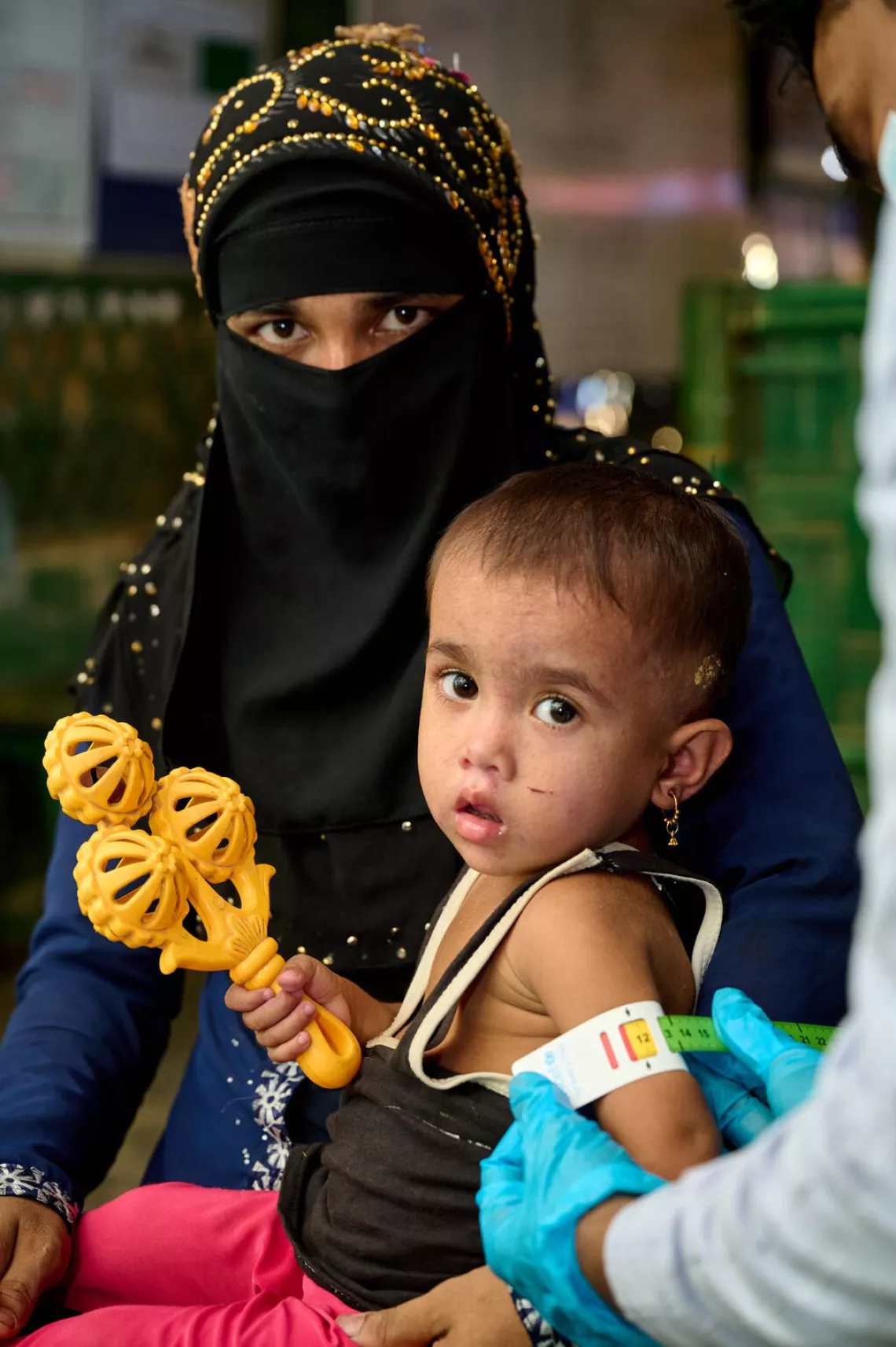 A health worker measures mid-upper arm circumference of Nur Kayas with a colour coded tape.