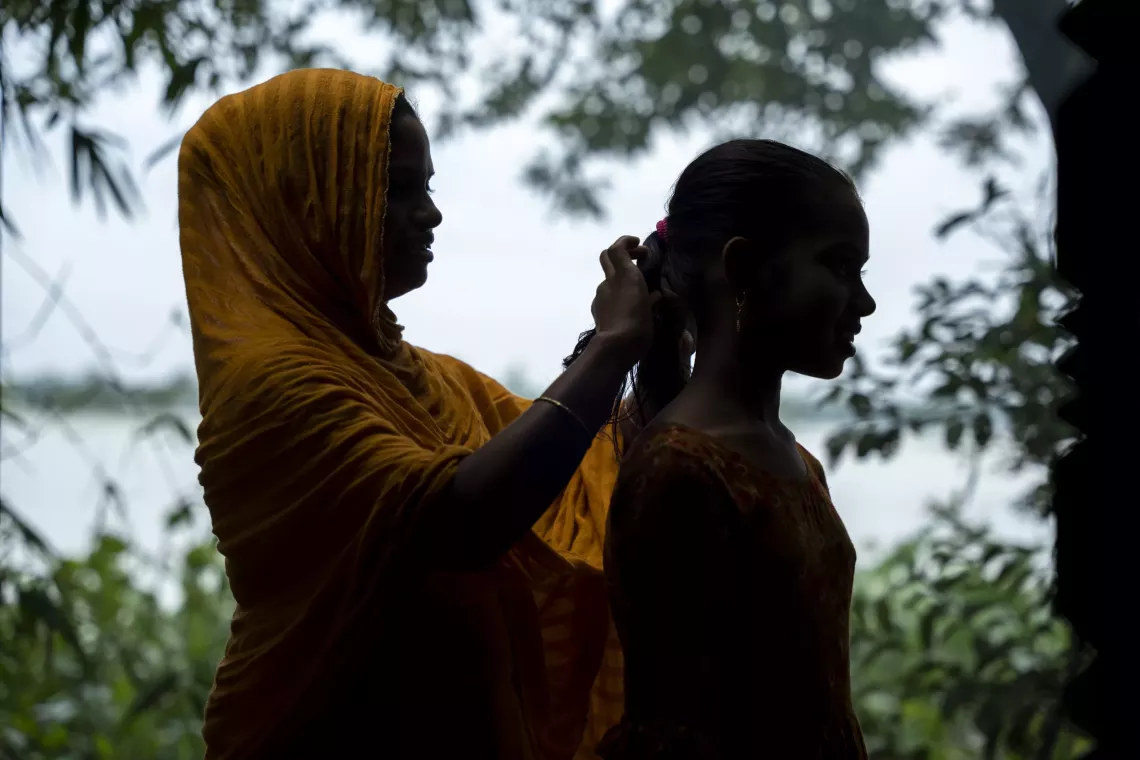 Sufia helps Tawhida tie her hair. With her husband abroad, she is the main caretaker of three children in the family. Though not receiving an education, she wants her daughter to achieve the dream of becoming a doctor. 