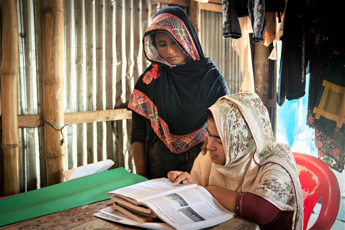 Tahmina at home, studying. Her mother, Arefa, says she will do all she can to support her children to get educated.