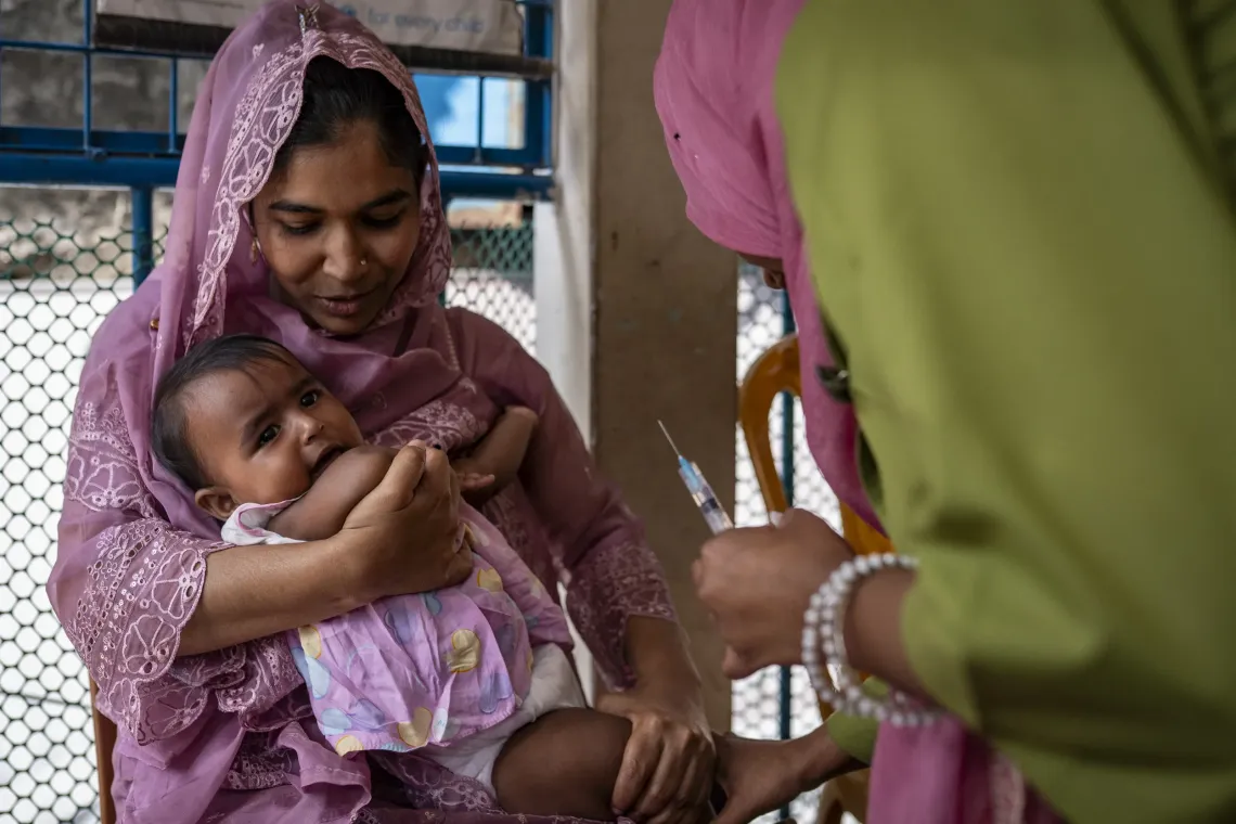 Maushami coaxes Ayesha as she is about to receive the measles-rubella vaccine. 
