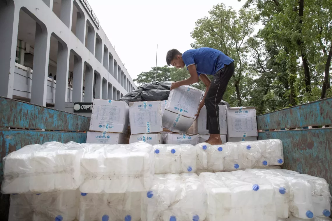 Workers load UNICEF-supported jerry cans and water purification tablets to deliver support to flood-affected people 