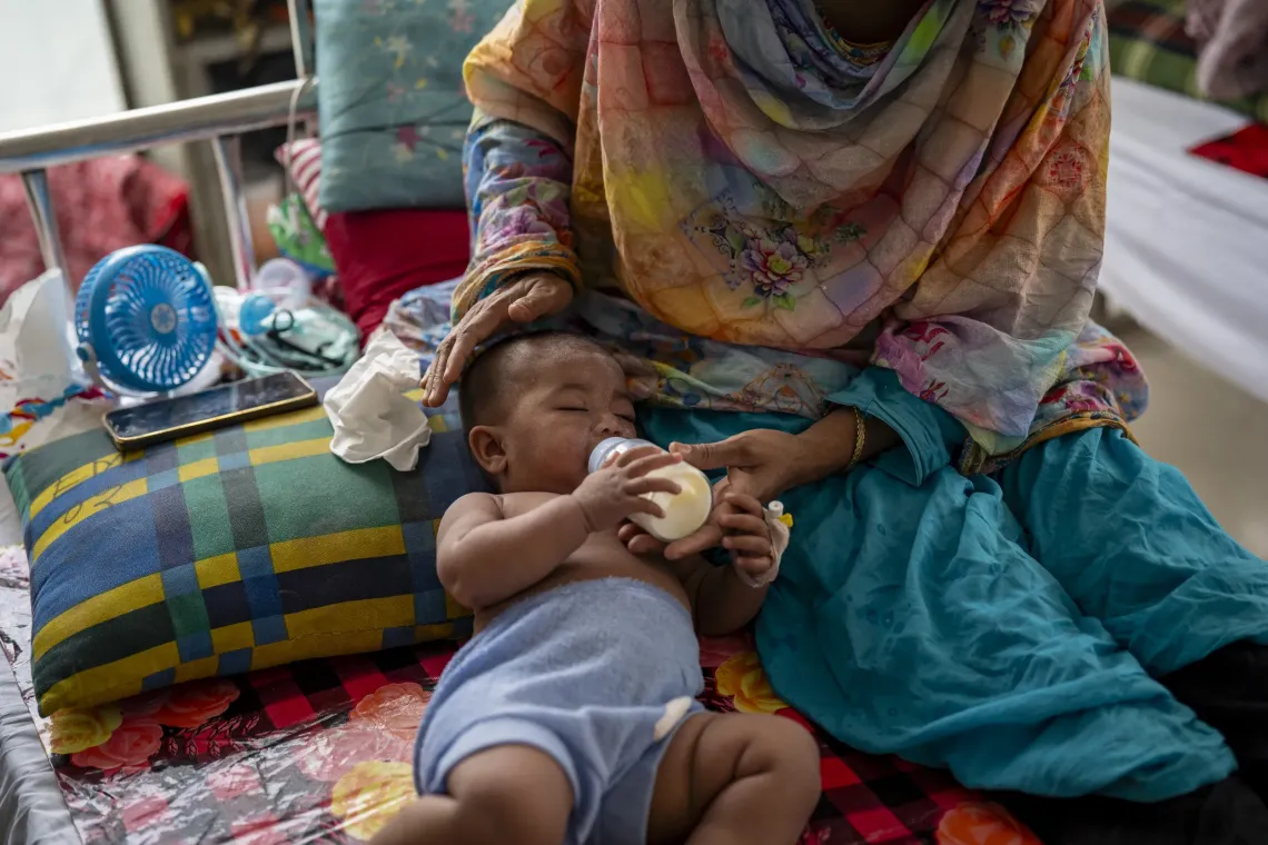 Amena, 8 months, drinks milk beside her parent while recovering at Mohakhali DNCC Hospital