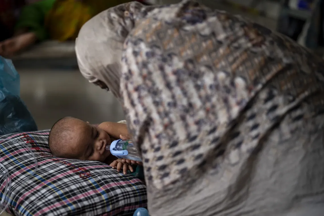 One-year-old Ayatullah drinks from a feeder under his parents&rsquo; watch at Mohakhali DNCC Hospital.