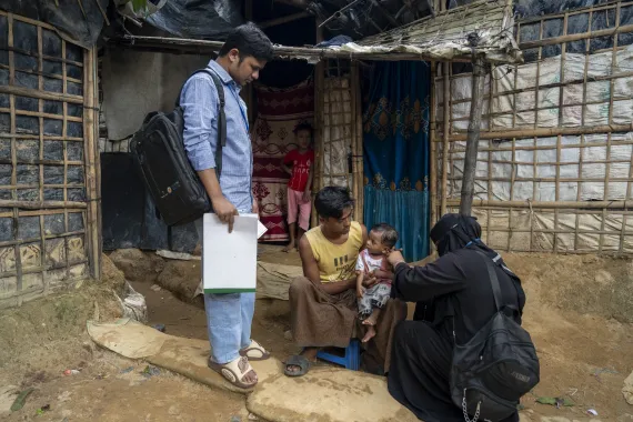 Community nutrition volunteers Shafiqa and Omar conduct a routine screening of Aziz Khan at his home.