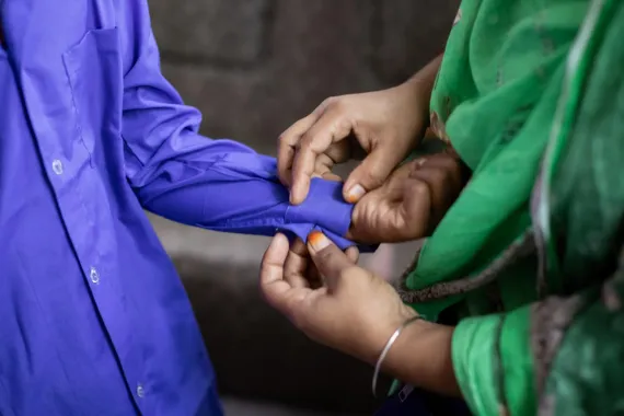 Abrar’s khaala (aunt) helps him button up his shirt as he gets ready for school.