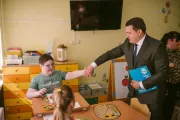 Представитель ЮНИСЕФ здоровается с мальчиком за руку