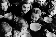 Около 1946 года в Греции улыбающиеся девочки из Патр, портового города на северо-западе страны, едят свою первую порцию еды, предоставленную ЮНРРА, из металлических мисок.