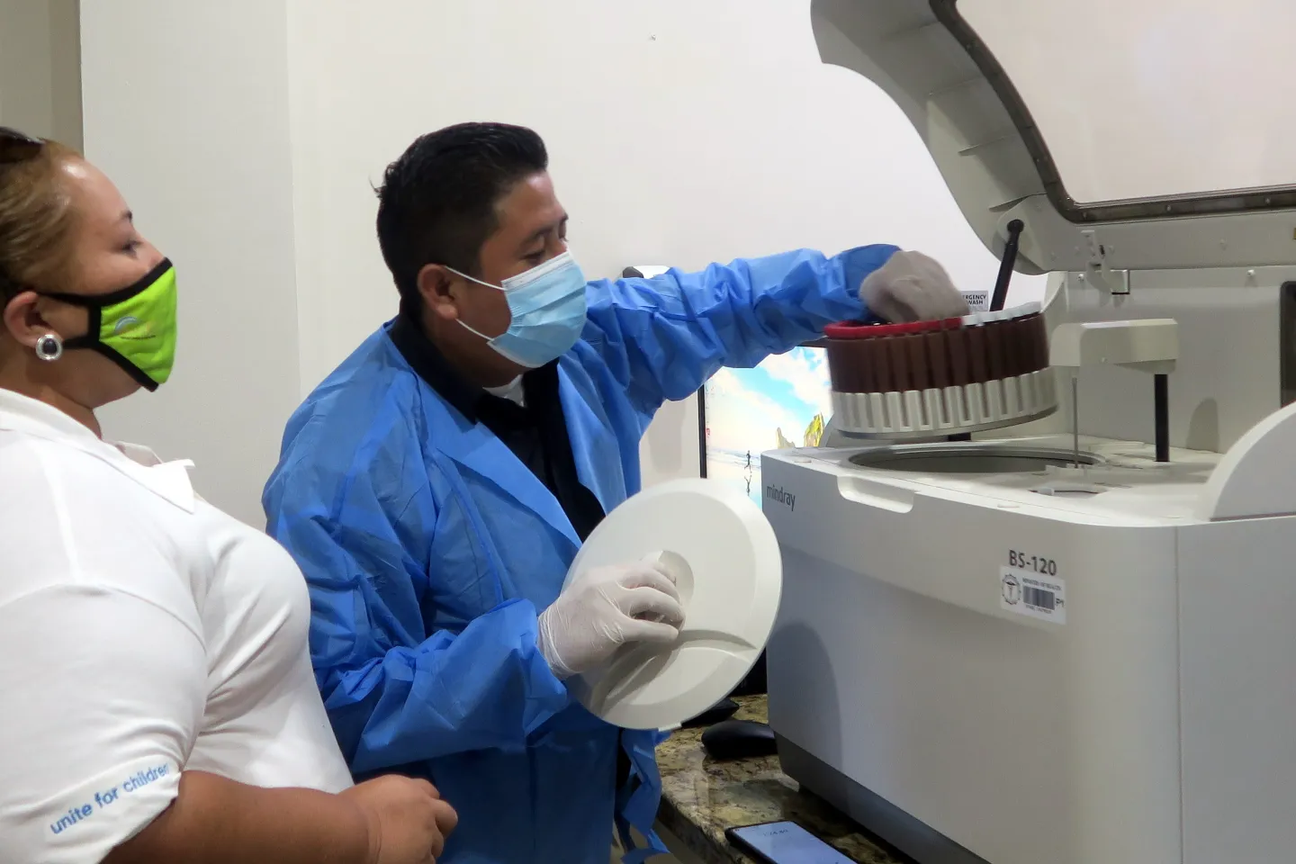 UNICEF Belize: a lab technician shows a UNICEF staff how to operate testing equipment in a lab.