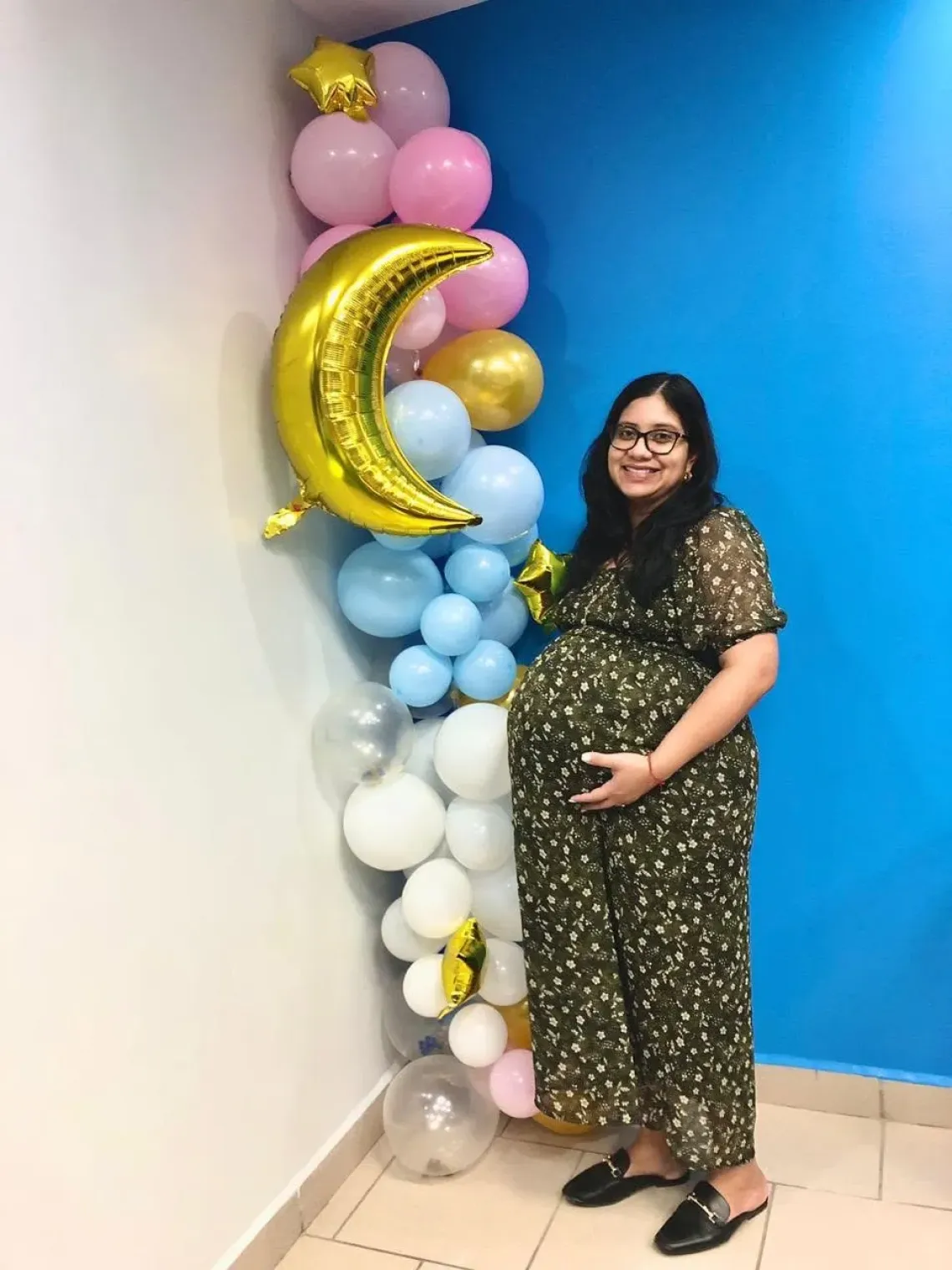 woman stands near wall holding her pregnant belly
