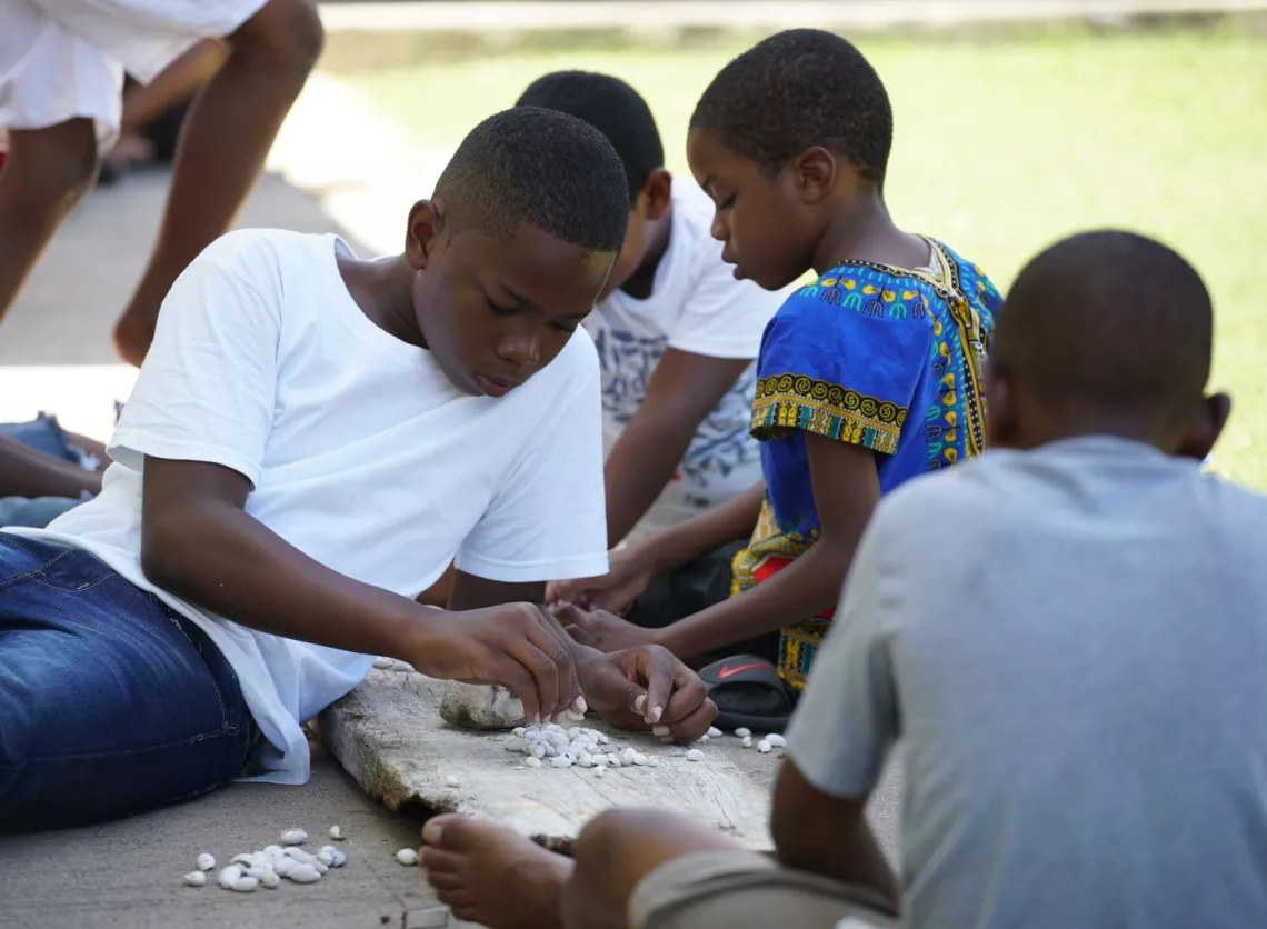 A group of boys preparing sea shells that will be attached to the knees of their costumes