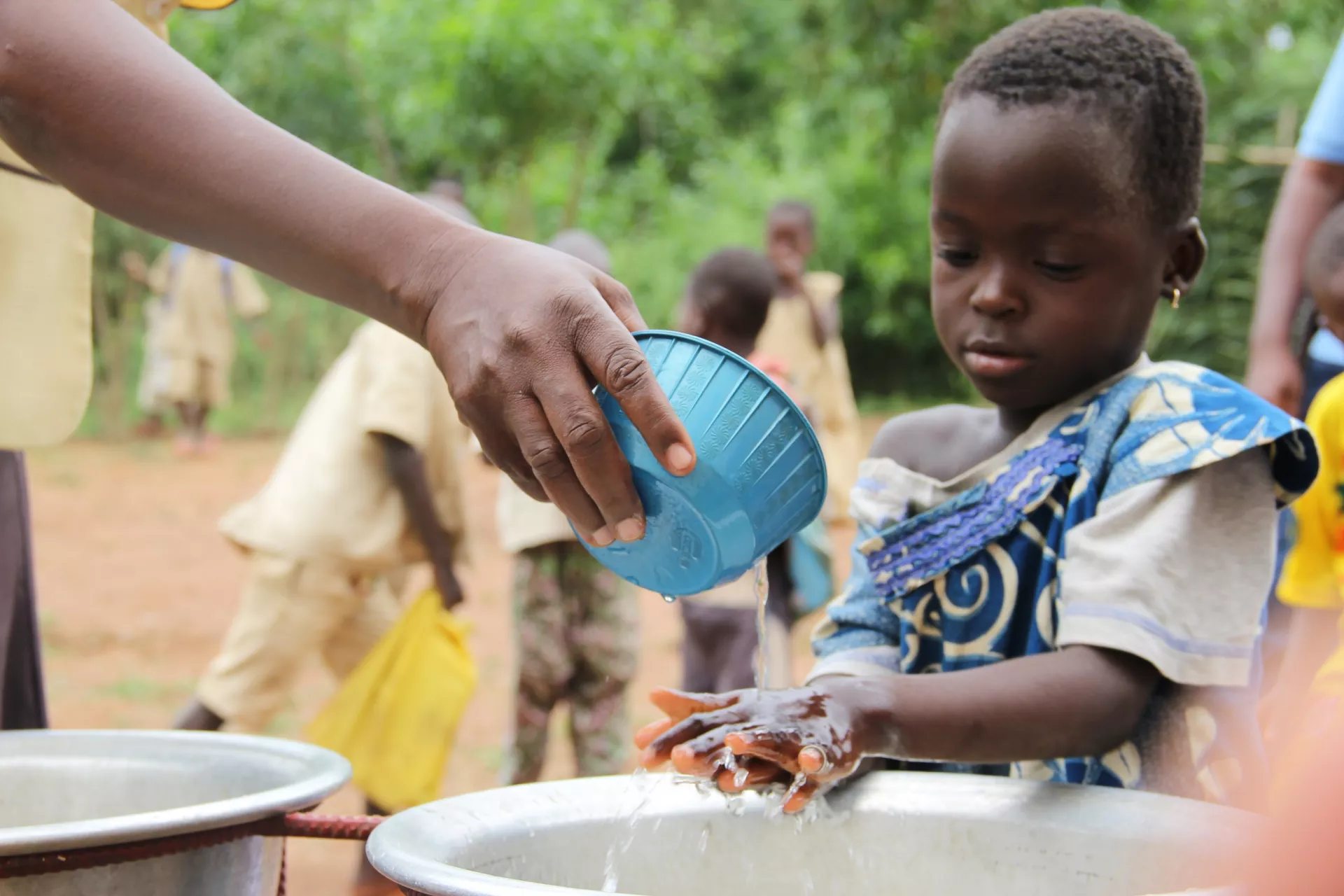 Une petite fille d'une &eacute;cole maternelle pour les enfants de 2 &agrave; 3 ans se lavant les mains dans une bassine