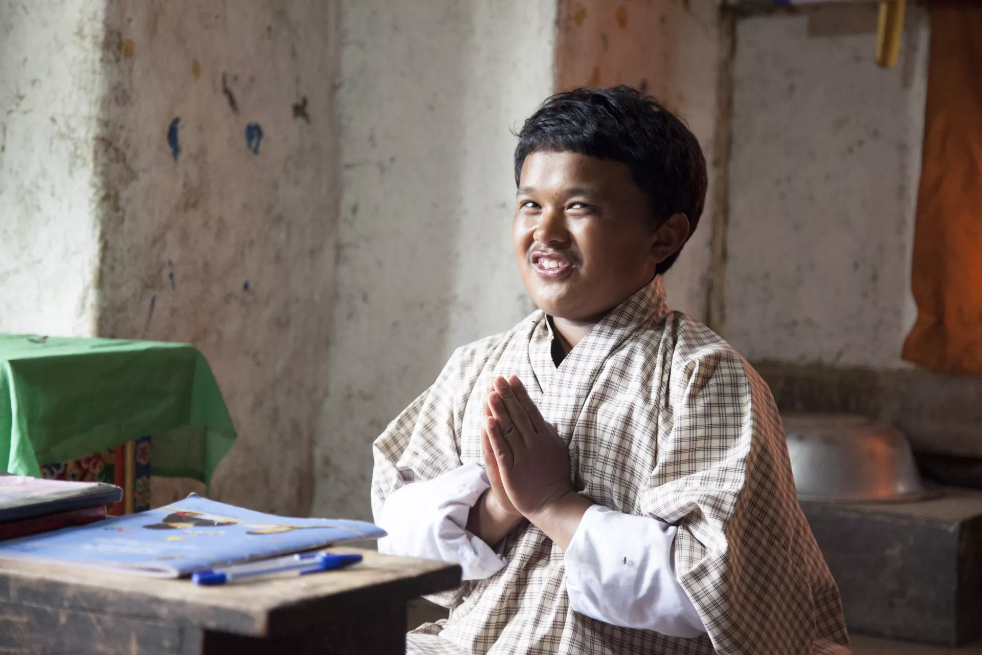 A boy with folded hands and books