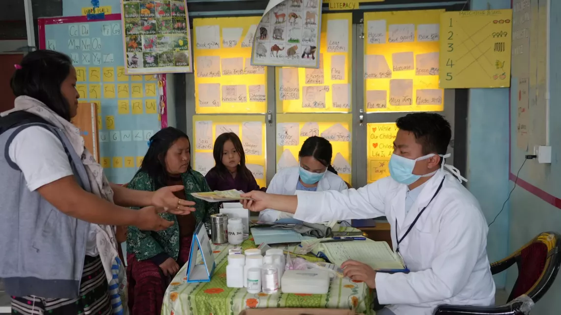 A health worker hands over a book to a woman. 