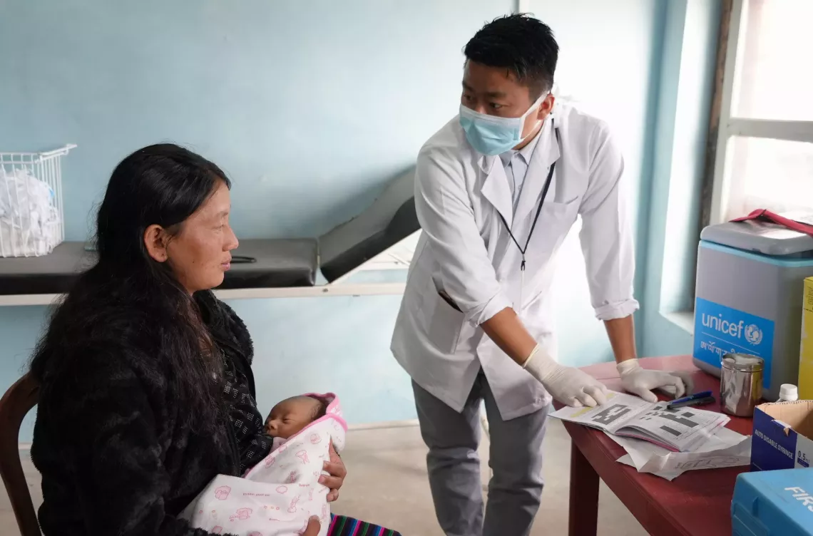 A health worker interacts with a mother holding  a child 
