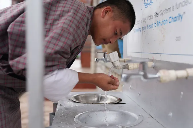 Student drinking water from a school water filtration station.