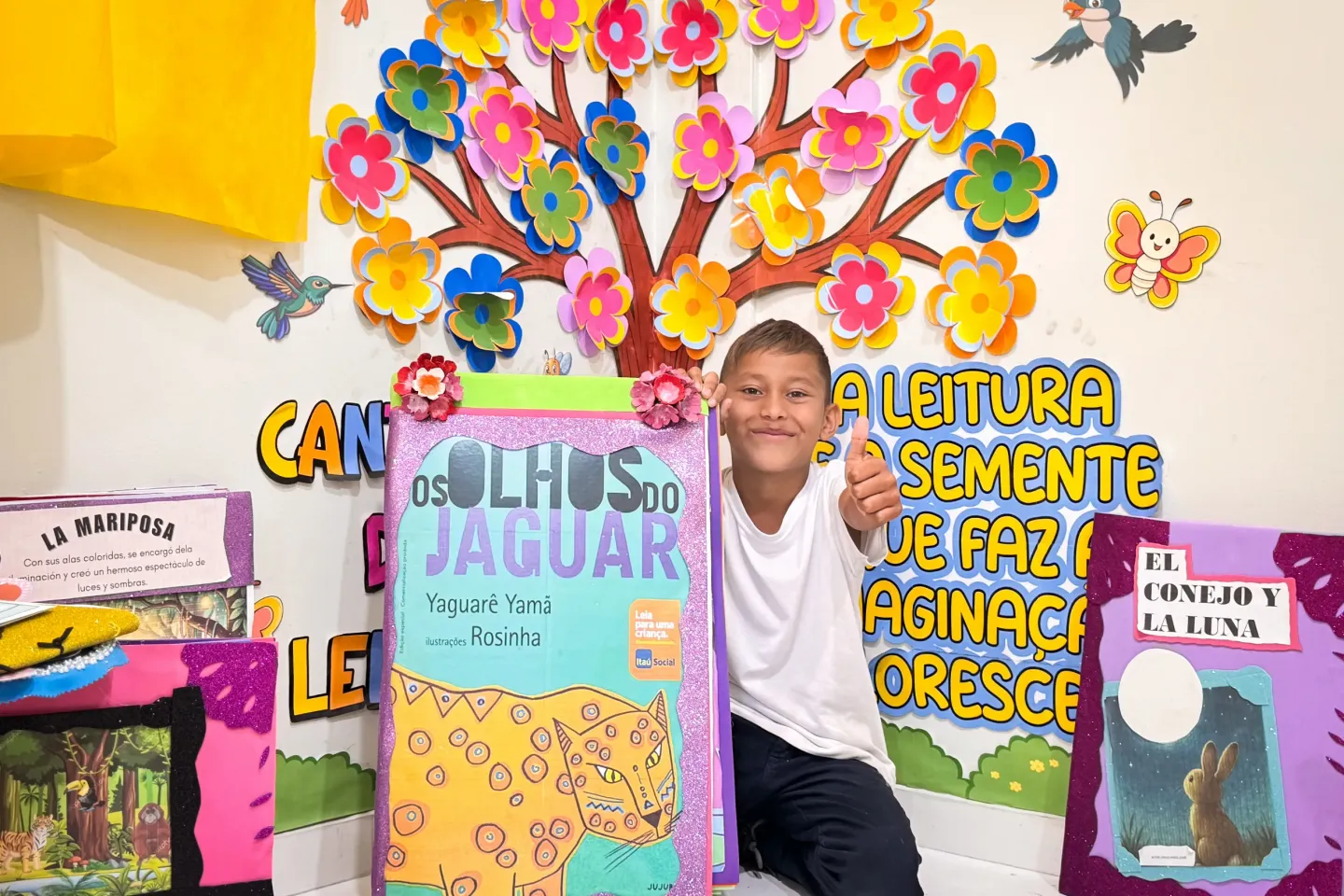 menino com uniforme escolar e rodeado de livros e colagens coloridas