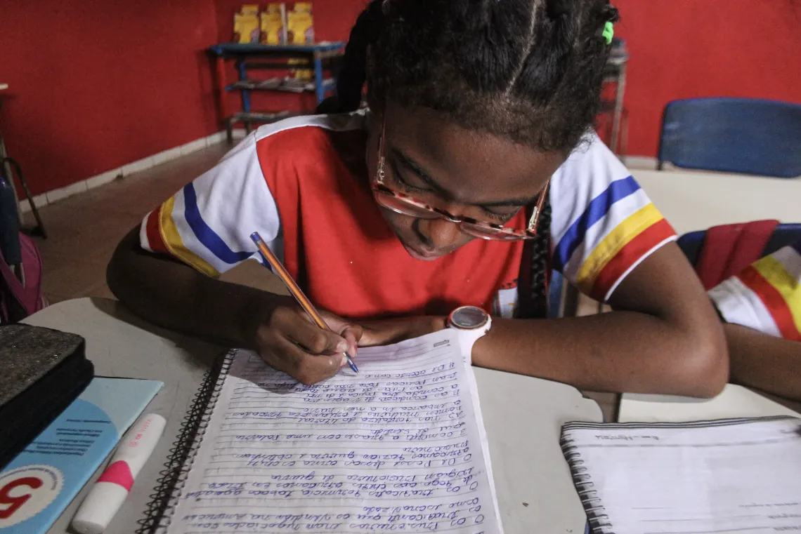 menina escreve em caderno
