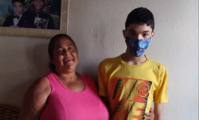 Na foto, m&atilde;e e filho olham para a c&acirc;mera. A m&atilde;e est&aacute; sorrindo, o menino est&aacute; de m&aacute;scara.