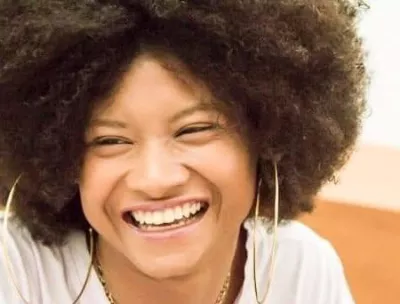 Foto mostra o rosto de uma jovem sorridente