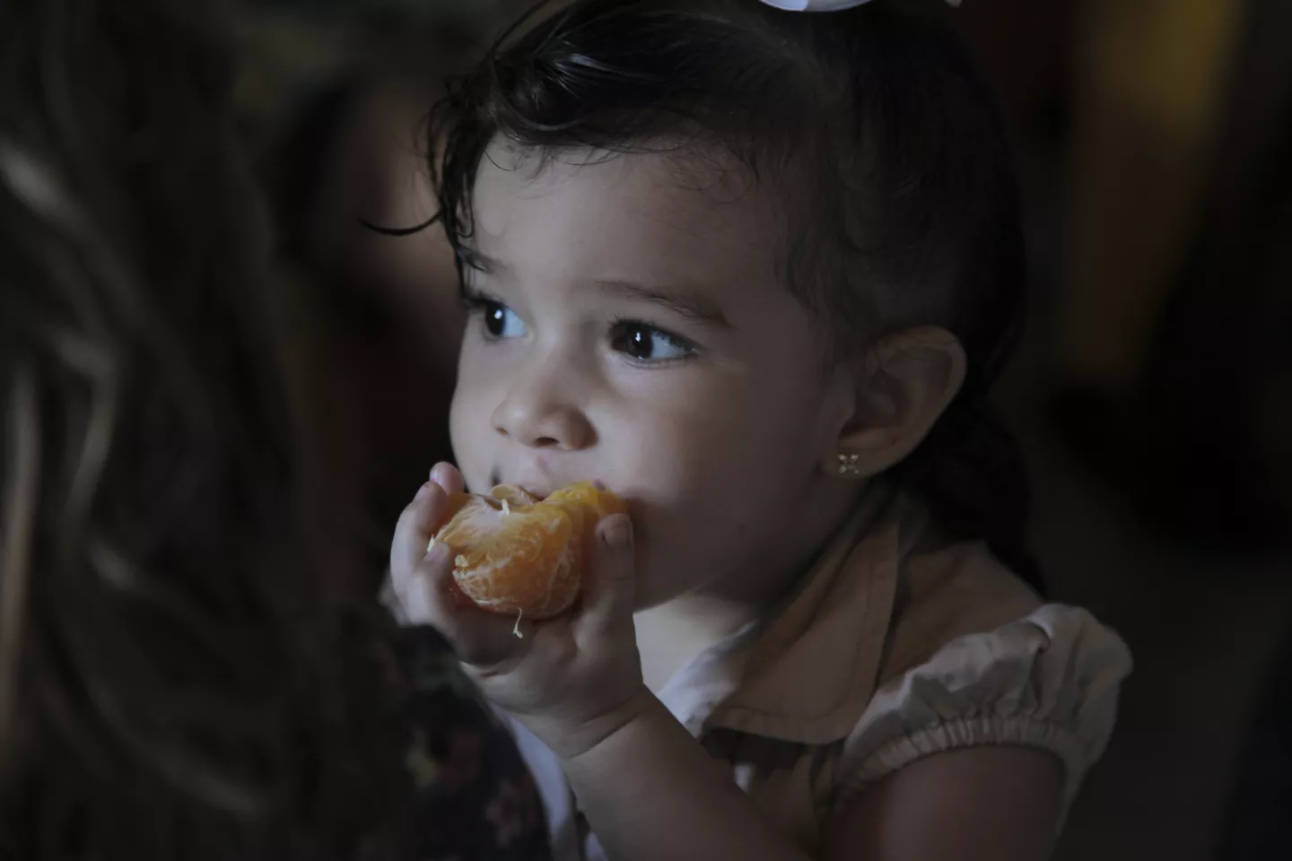 Foto mostra uma menina pequena comendo uma tangerina