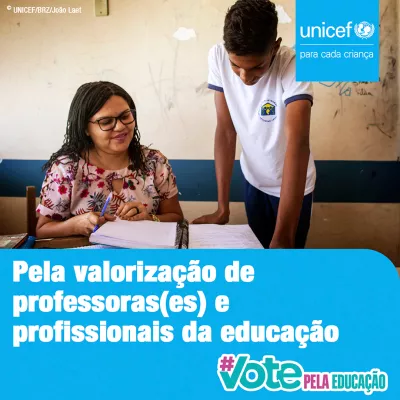 Card da campanha #VotePelaEduca&ccedil;&atilde;o - No canto superior direito aparece o logo do UNICEF. No rodap&eacute; da imagem aparece o logo da campanha e est&aacute; escrito Pela valoriza&ccedil;&atilde;o de professoras(es) e profissionais da educa&ccedil;&atilde;o - Foto mostra uma professora em sala de aula explicando alguma coisa para um aluno. Ela est&aacute; sentada e ele est&aacute; em p&eacute; ao lado dela, apoiado na mesa.