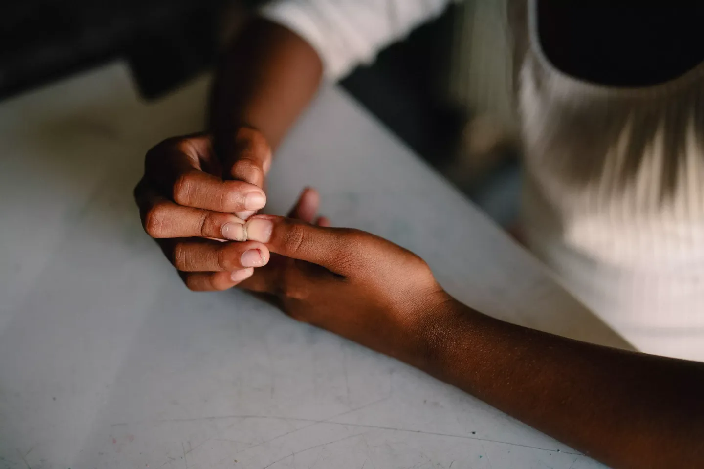M&atilde;os e bra&ccedil;os de crian&ccedil;a sobre uma mesa