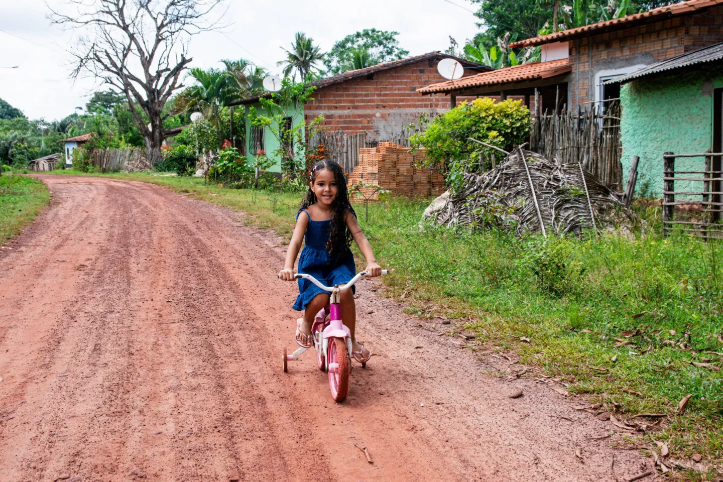 menina em cima de bicicleta rosa em estrada de terra