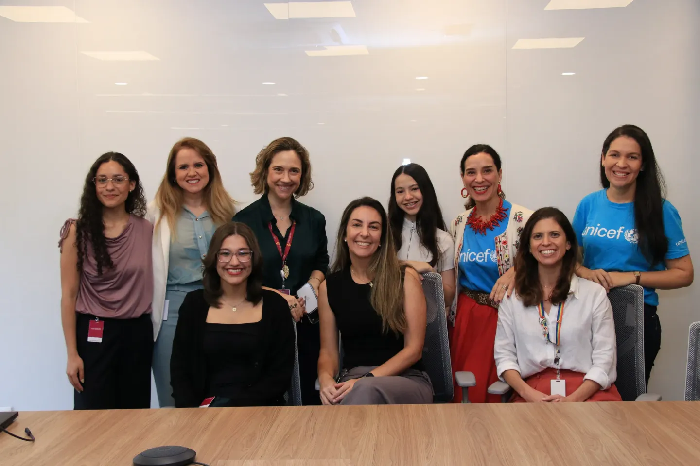 grupo de mulheres e meninas posa para foto atr&aacute;s de mesa