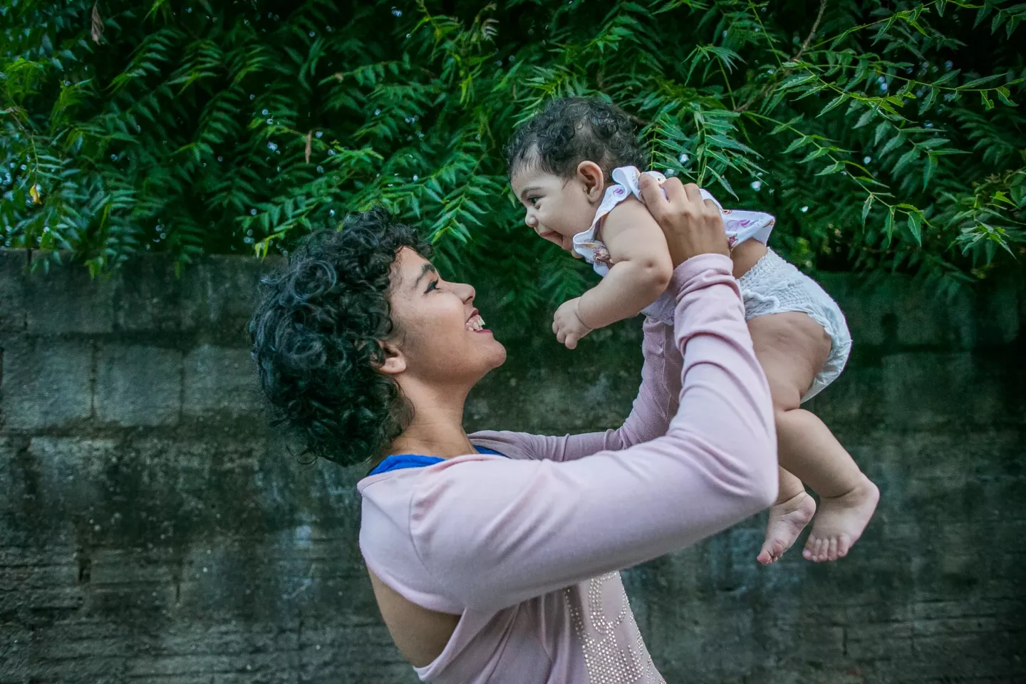 Mulher segura beb&ecirc; nos bra&ccedil;os acima da cabe&ccedil;a