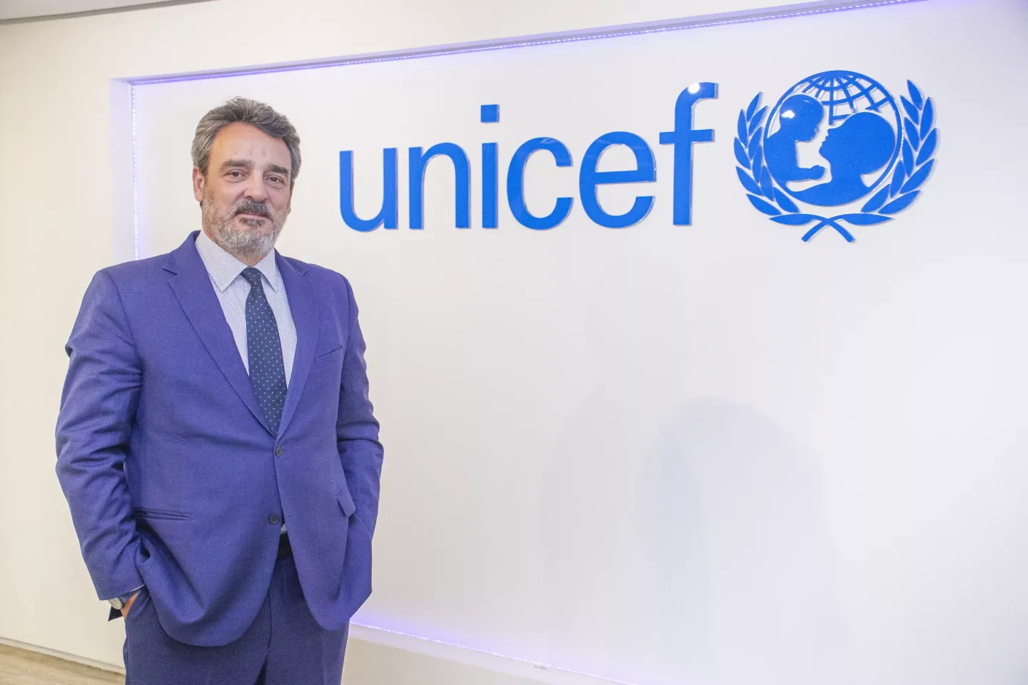 homem de terno azulem frente a uma logomarca do UNICEF