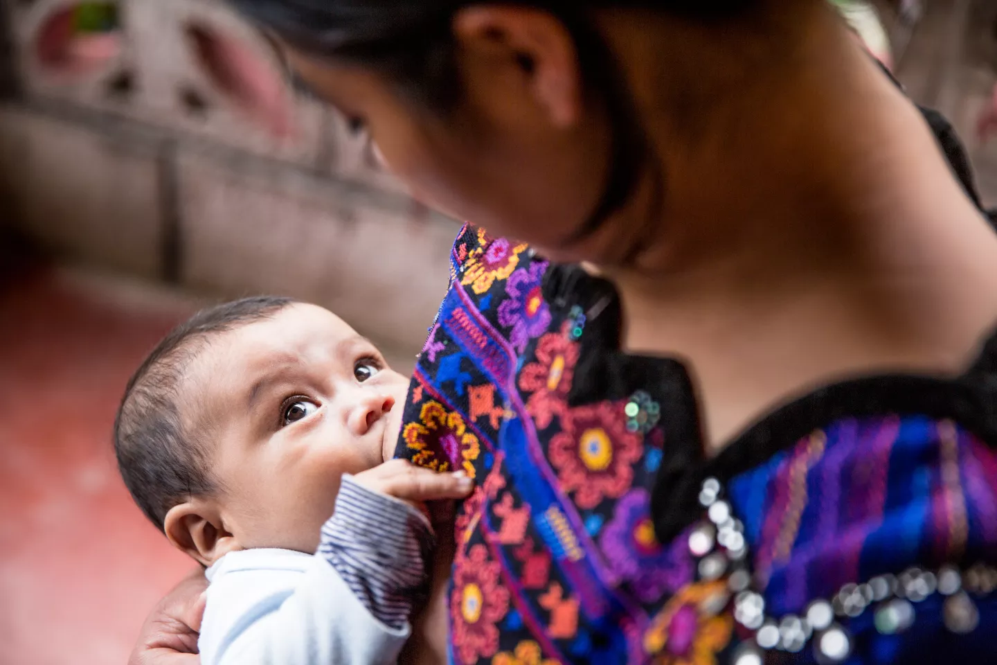 uma m&atilde;e amamenta seu beb&ecirc; enquanto eles se olham nos olhos