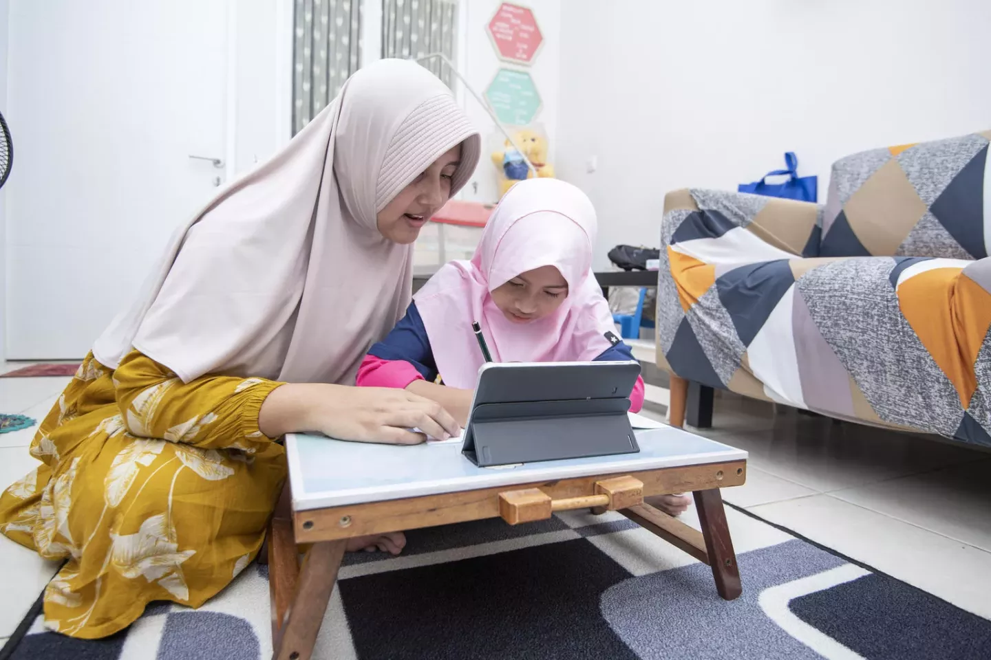 Une m&egrave;re aide sa fille utilisent une tablette num&eacute;rique