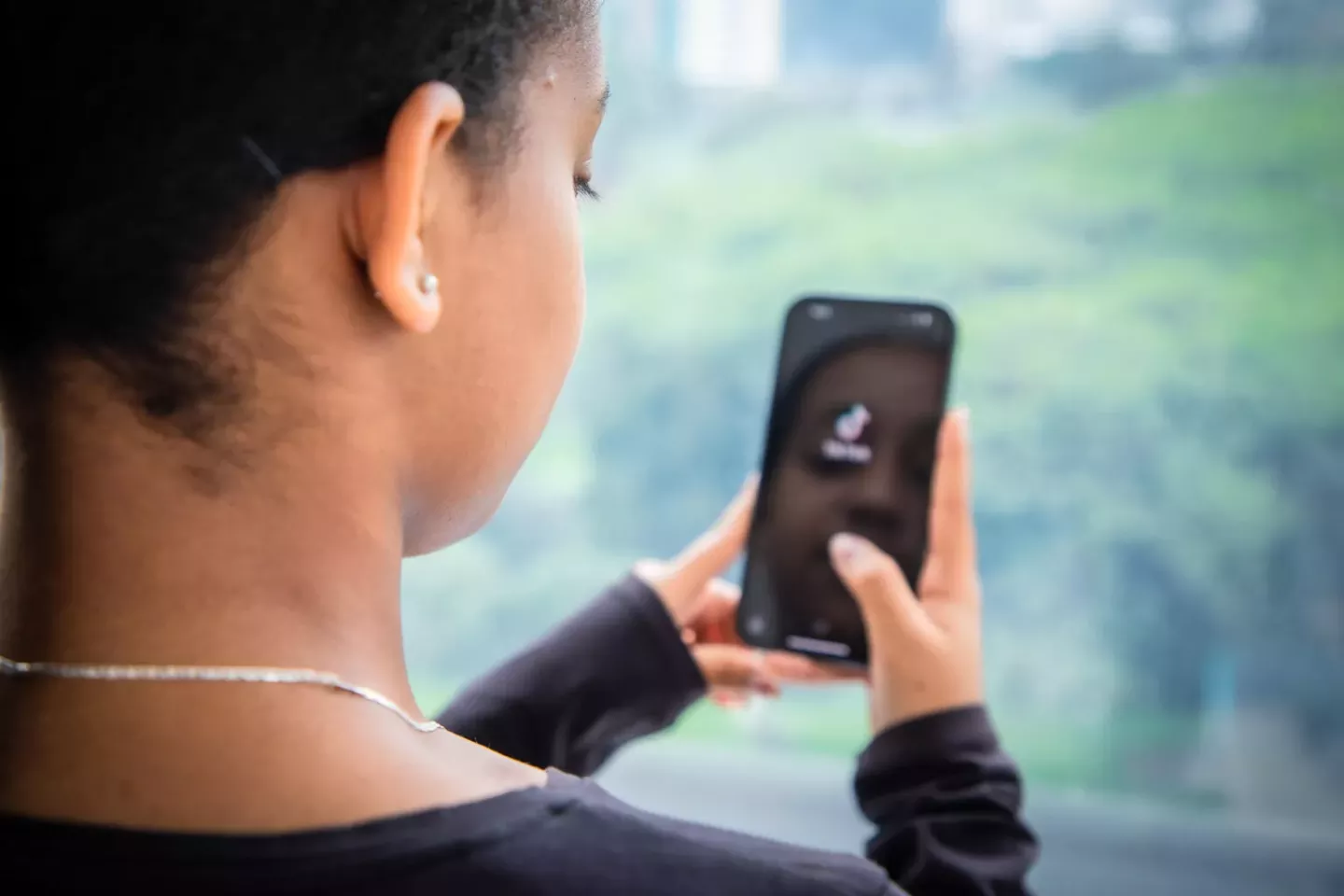 menina negra de costas segura celular