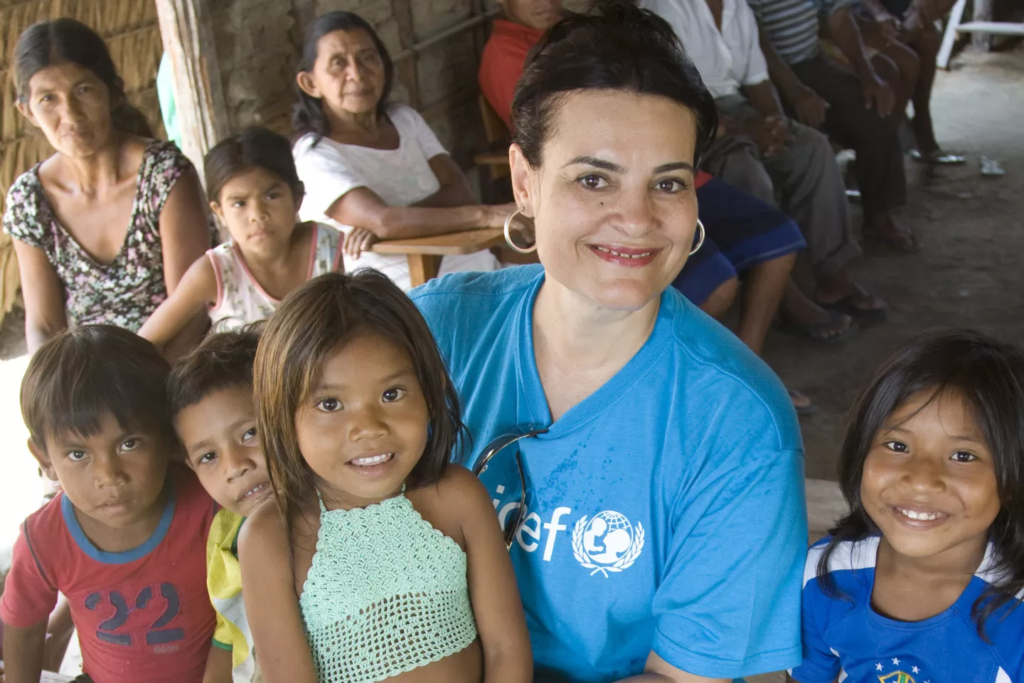 A chefe de Sa&uacute;de do UNICEF no Brasil, Cristina Albuquerque, usando uma camiseta do UNICEF, segura uma crian&ccedil;a no colo. Ao redor dela est&atilde;o outras crian&ccedil;as.