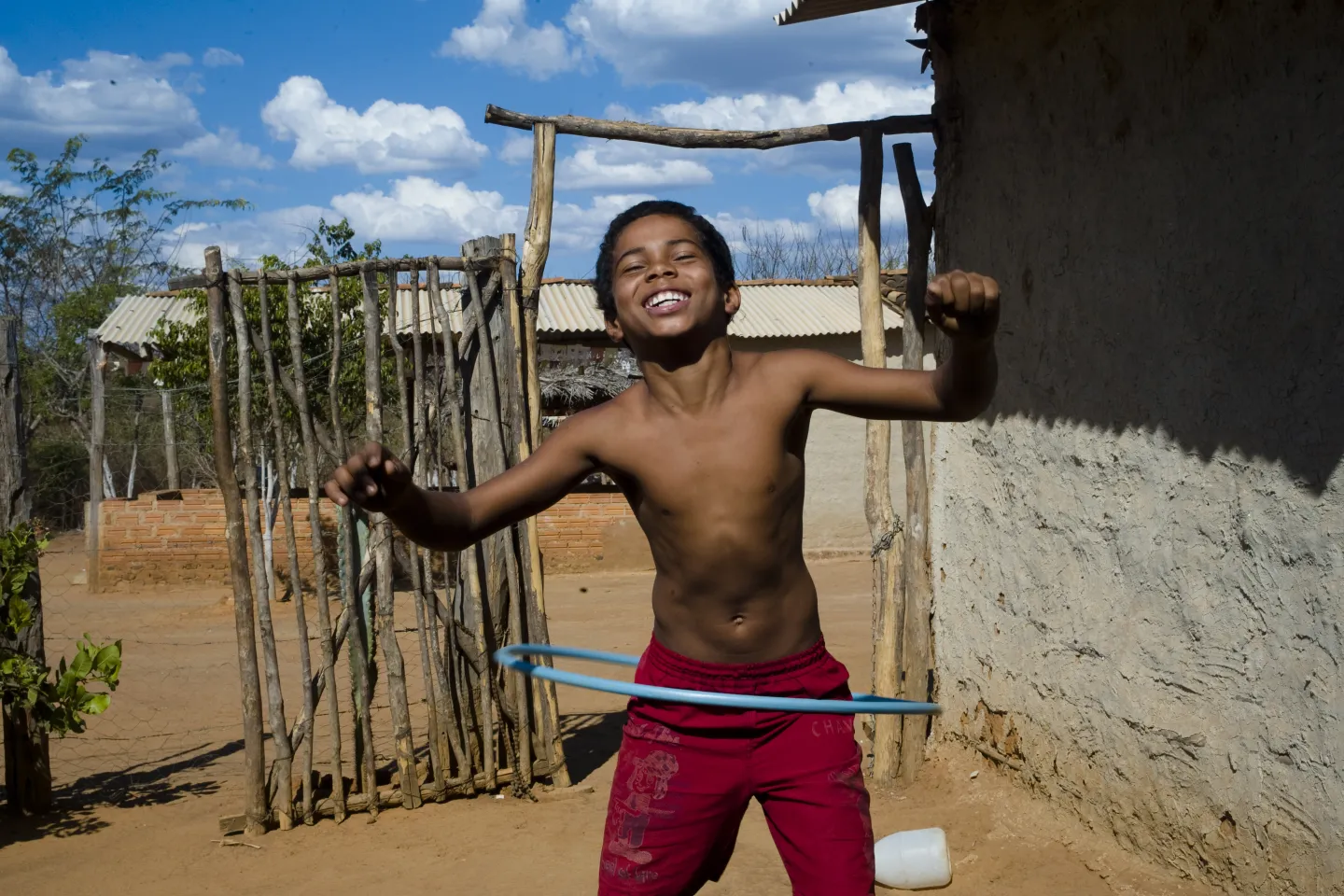 menino brinca com bambol&ecirc;. ele est&aacute; sem camisa em um ambiente rural