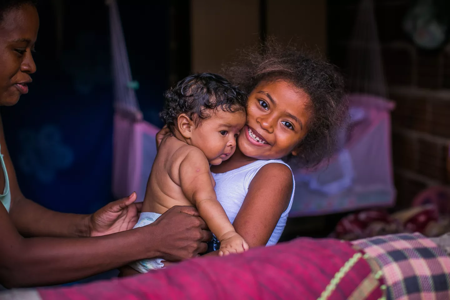 uma menina pega sua irm&atilde;zinha beb&ecirc; no colo. 