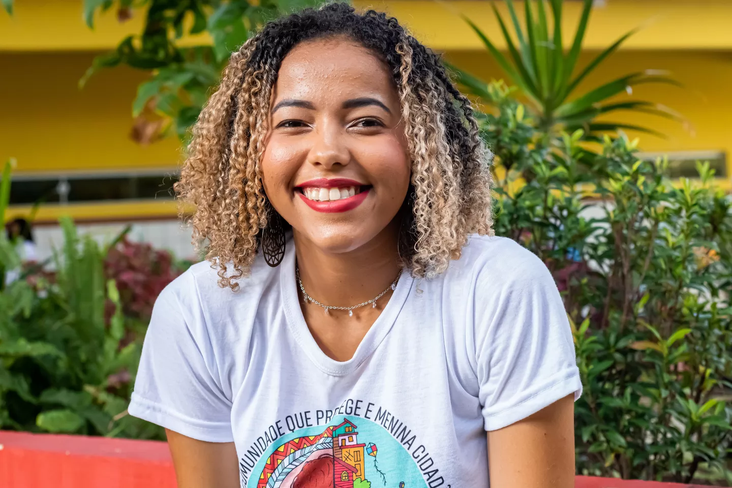 Foto mostra uma jovem sorridente olhando para a c&acirc;mera