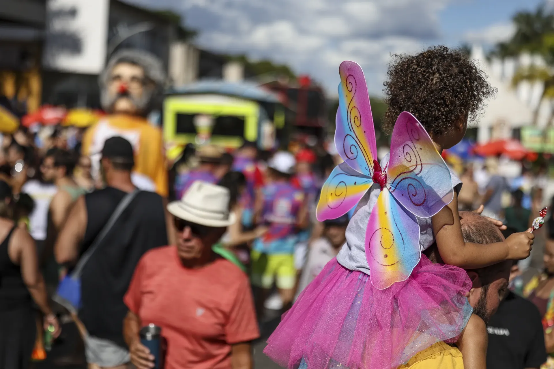 crian&ccedil;a no ombro de um adulto durante um carnaval