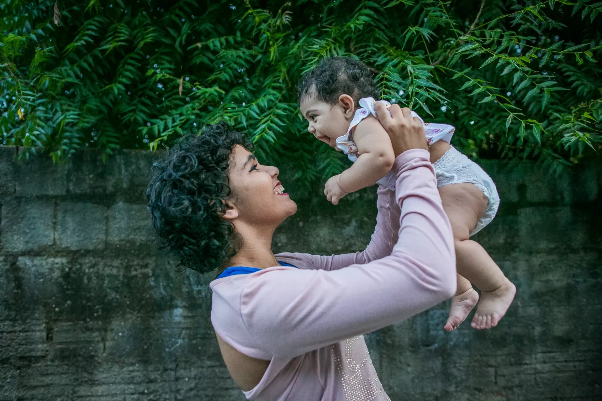 Mulher segura beb&ecirc; nos bra&ccedil;os acima da cabe&ccedil;a