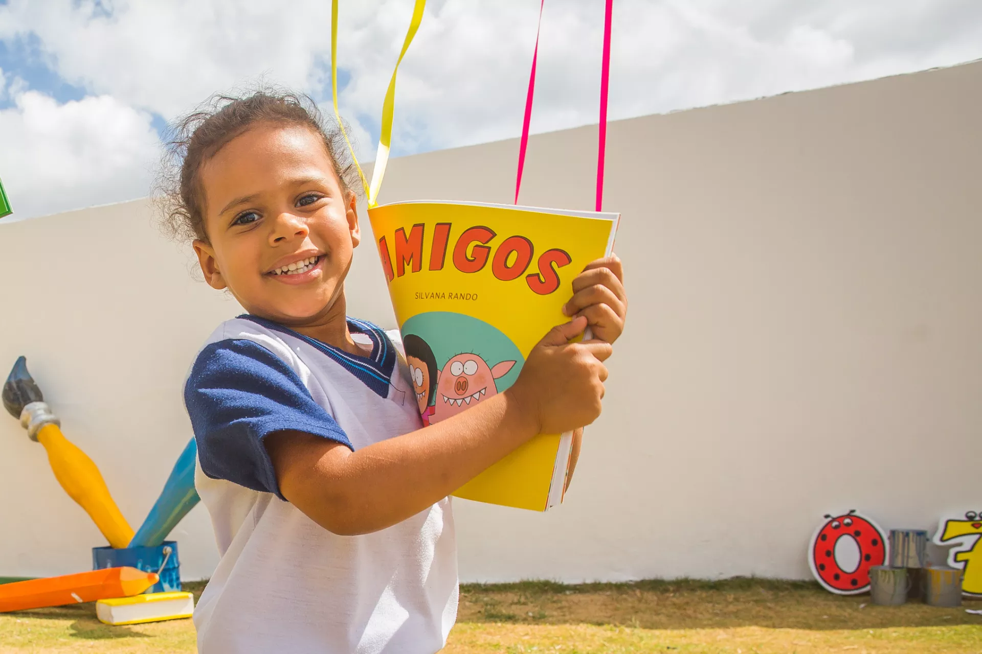uma menina segura um livro fechado. ela olha para a c&acirc;mera enquanto mostra o livro.