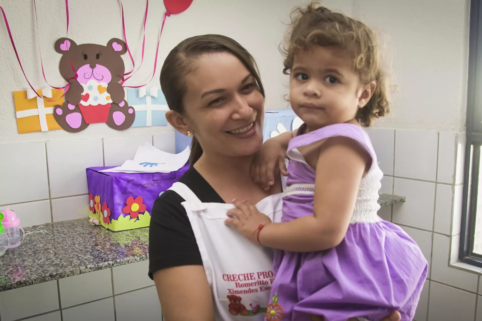 Professora de creche segura aluna no colo