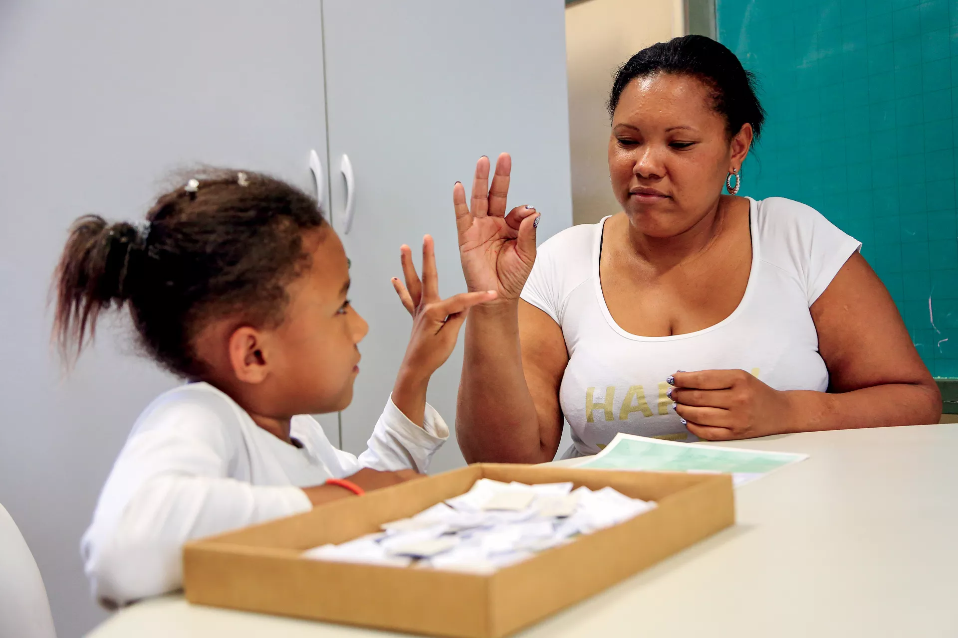 a foto mostra uma menina e sua m&atilde;e conversando em Libras. A menina tem defici&ecirc;ncia auditiva.