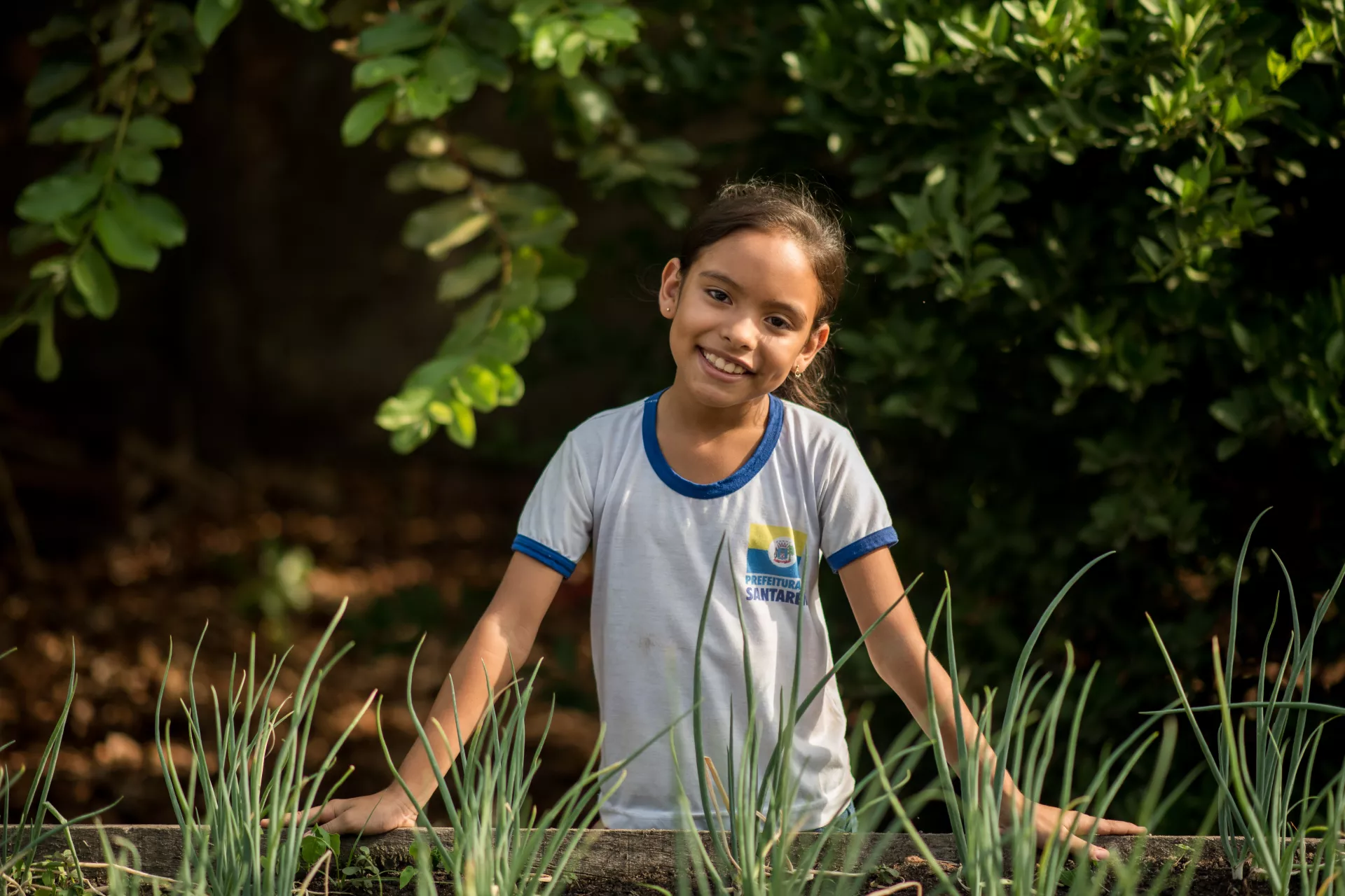 menina mostra a horta do seu col&eacute;gio