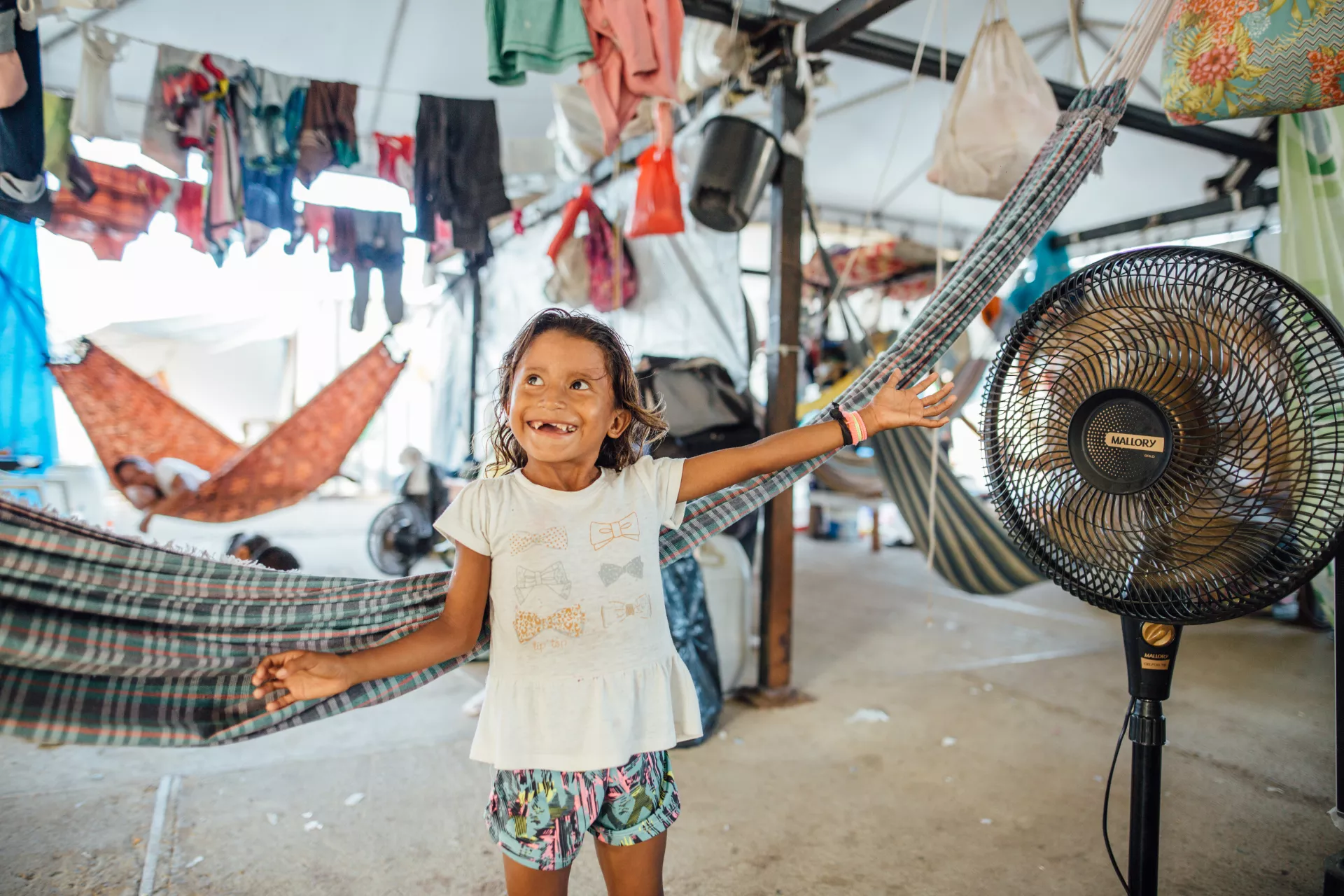 uma menina est&aacute; em um espa&ccedil;o com redes. ela est&aacute; encostada em uma rede, sorrindo