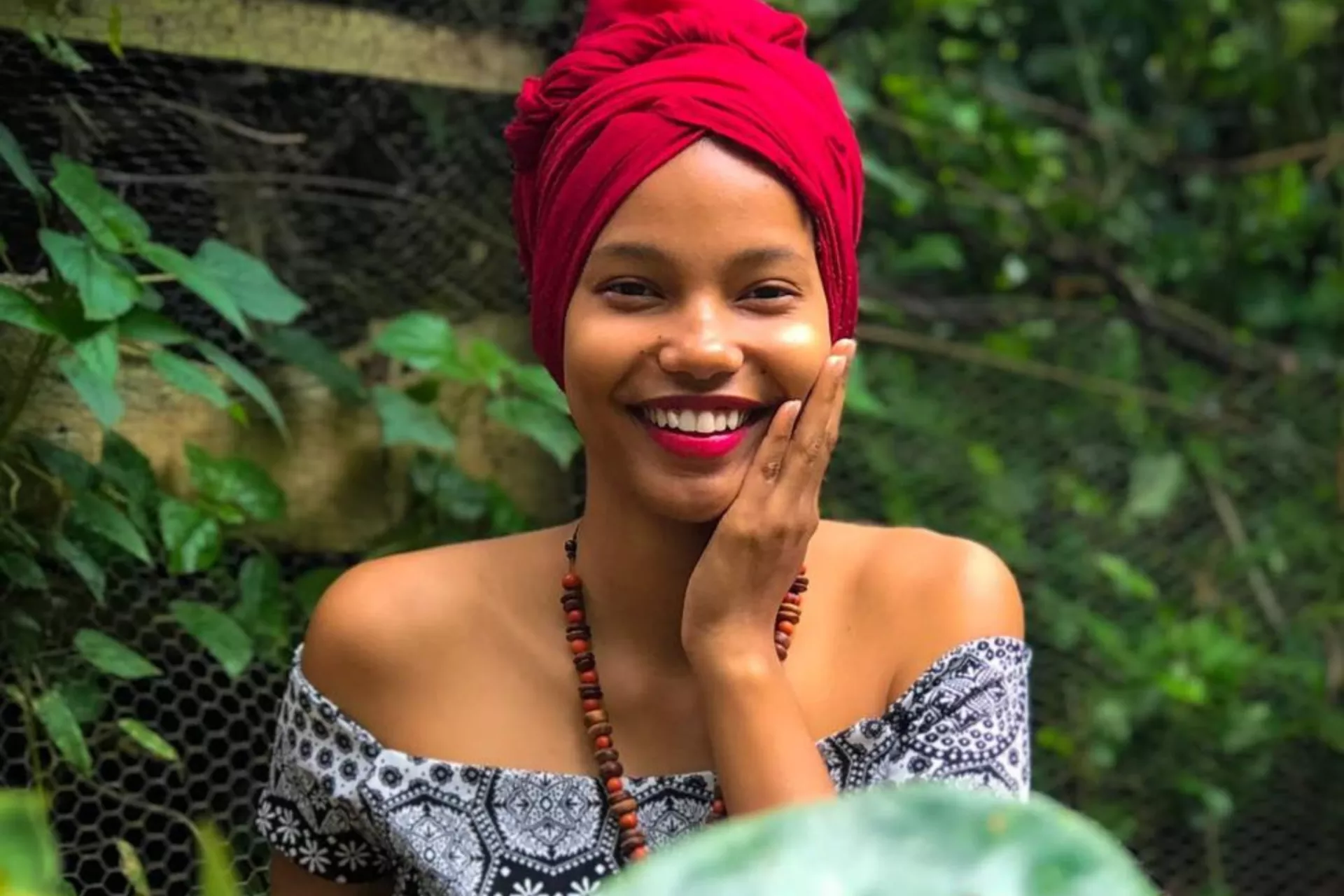 Ludimila olha para a foto sorrindo, ela est&aacute; com a m&atilde;o no rosto.