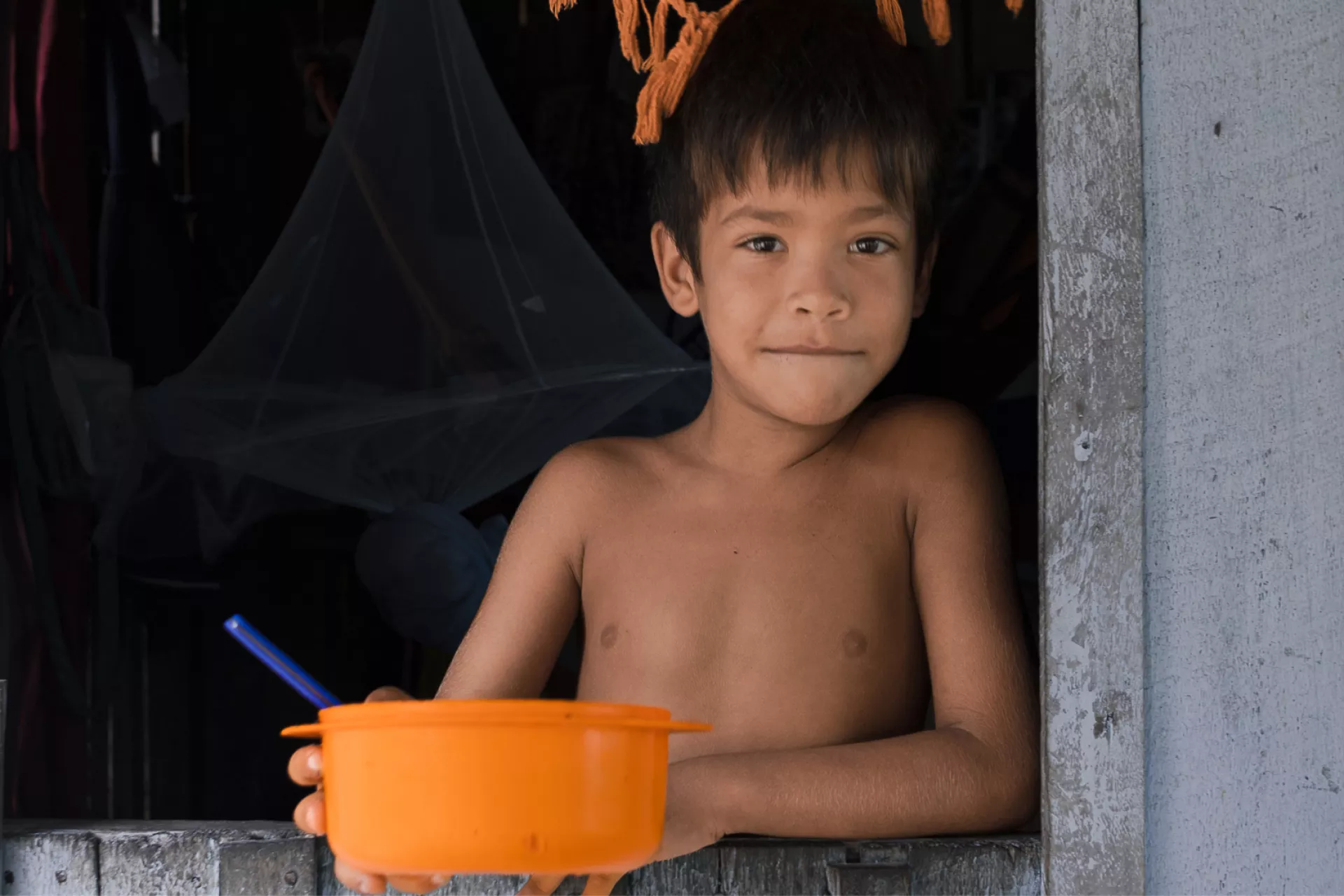 Foto mostra um menino segurando uma bacia