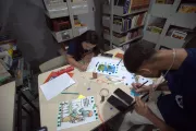 dois adolescentes fazendo trabalho em papel em uma mesa de biblioteca