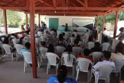 grupo de pessoas assiste a apresenta&ccedil;&atilde;o sentado em cadeiras brancas