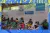Versão presencial da maratona Chama na Solução é feita exclusivamente para crianças e adolescentes refugiados e migrantes que vivem nos espaços Súper Panas de Manaus. Foto: crianças e adolescentes estão sentados em carteiras escolares, as carteiras estão espaçadas e as pessoas estão de máscara